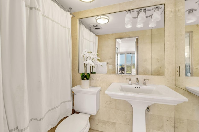 bathroom with a shower with curtain, tile walls, and toilet