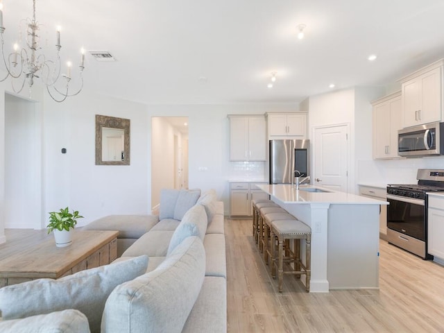 kitchen with a breakfast bar, stainless steel appliances, visible vents, open floor plan, and a sink