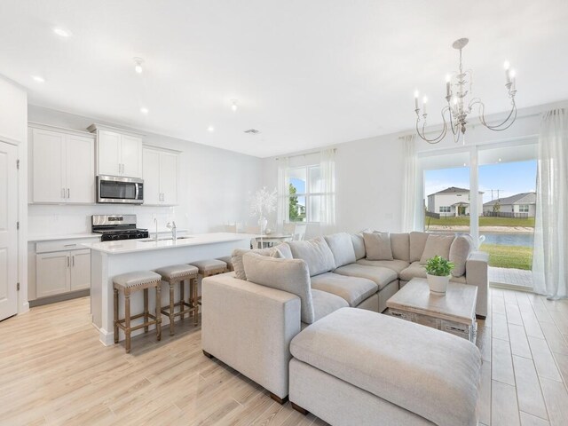 living area with light wood-style floors, recessed lighting, and a notable chandelier