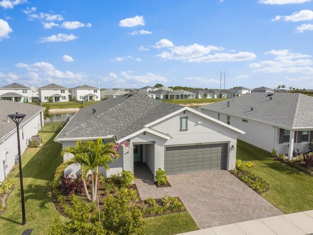 view of front of home featuring a garage, decorative driveway, a front yard, and a residential view