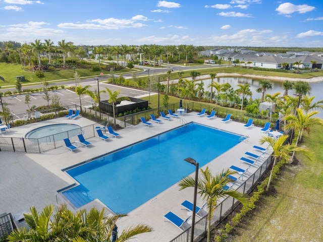 community pool with a water view, a patio area, a residential view, and fence