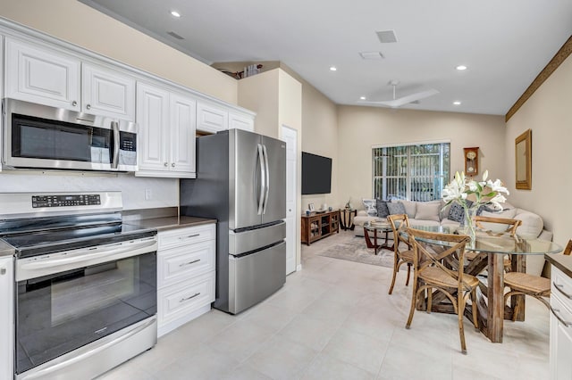 kitchen with light tile patterned floors, vaulted ceiling, stainless steel appliances, and white cabinets