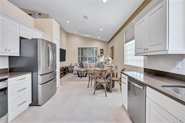 kitchen featuring lofted ceiling, light tile patterned flooring, white cabinets, and appliances with stainless steel finishes