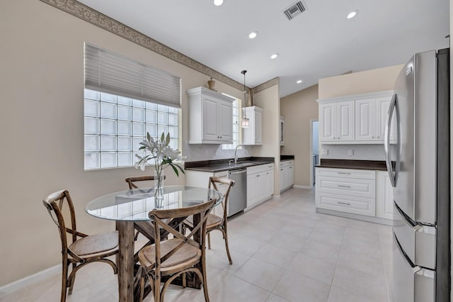 kitchen featuring pendant lighting, white cabinetry, sink, backsplash, and stainless steel appliances