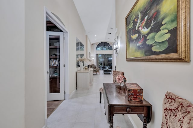 hallway featuring french doors, lofted ceiling, and light tile patterned floors