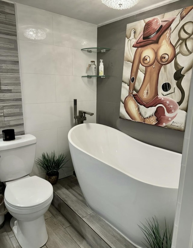 bathroom with wood-type flooring, tile walls, a bathtub, and toilet