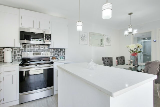 kitchen featuring appliances with stainless steel finishes, white cabinets, and decorative light fixtures