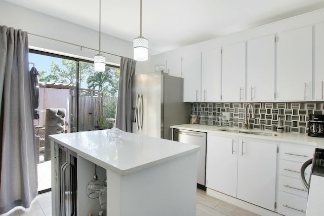 kitchen featuring sink, appliances with stainless steel finishes, pendant lighting, decorative backsplash, and white cabinets