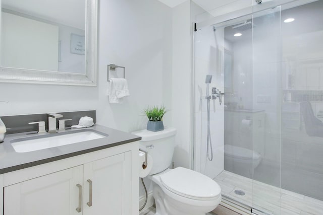 bathroom featuring vanity, a shower with door, and toilet