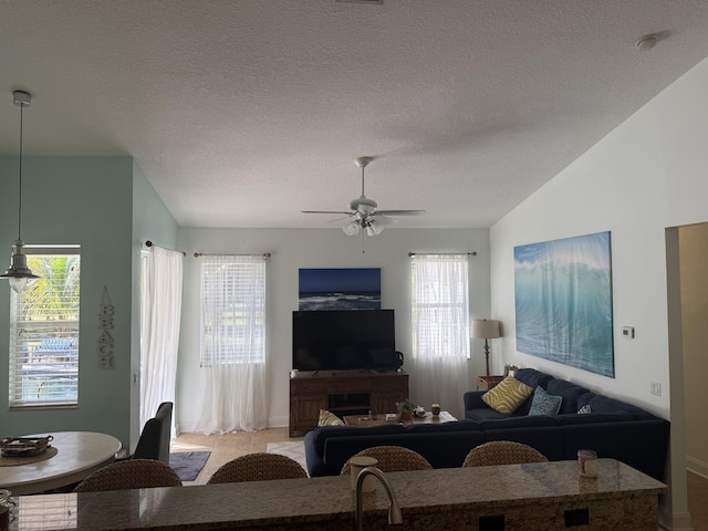 tiled living room featuring lofted ceiling, ceiling fan, and a textured ceiling