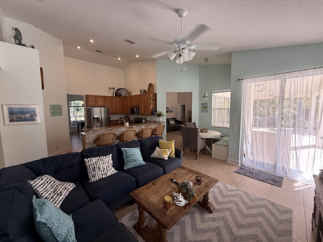 tiled living room with ceiling fan, high vaulted ceiling, sink, and a textured ceiling