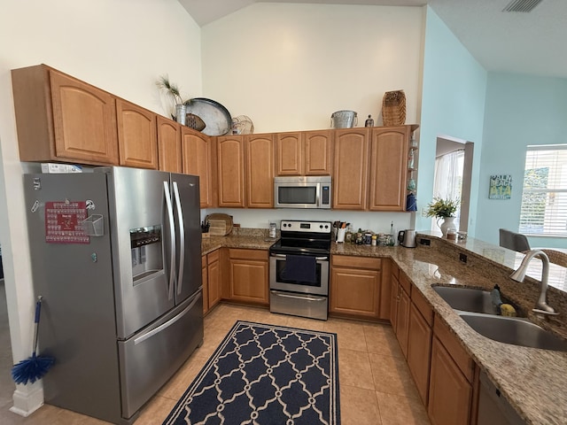 kitchen with sink, high vaulted ceiling, stone counters, and appliances with stainless steel finishes