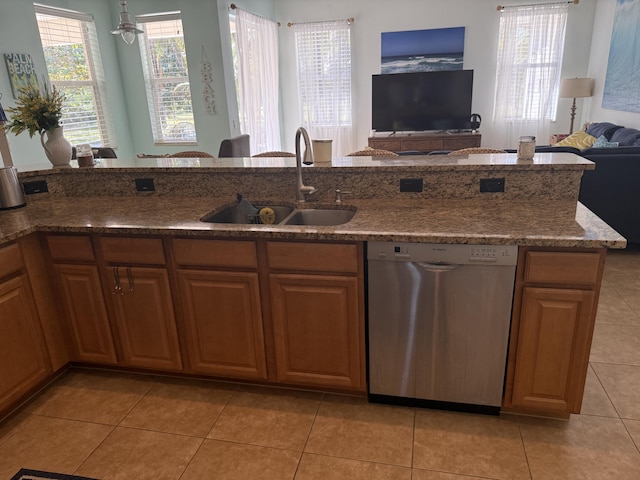 kitchen featuring dishwasher, sink, dark stone countertops, and light tile patterned floors