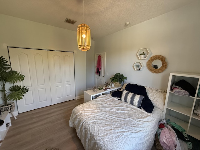 bedroom featuring dark wood-type flooring, a closet, and a textured ceiling