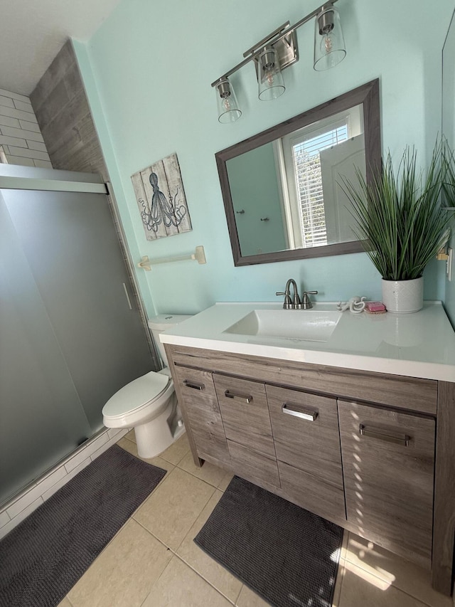 bathroom with toilet, vanity, a shower with door, and tile patterned flooring