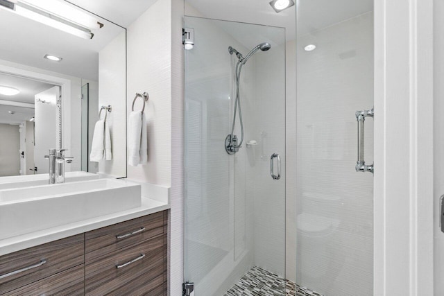 bathroom featuring a shower with door and vanity