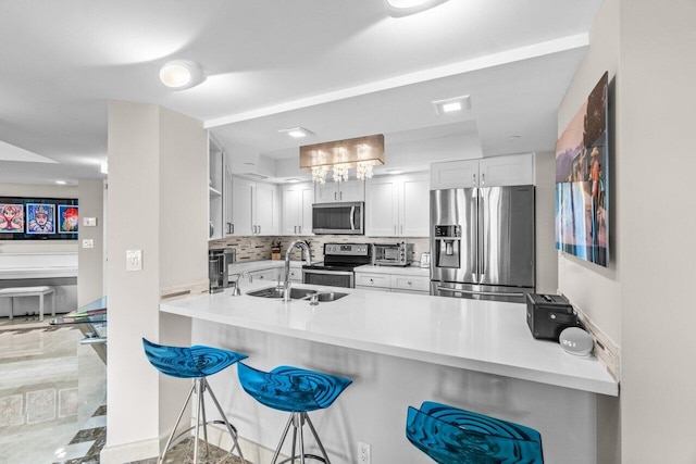 kitchen with sink, a breakfast bar area, white cabinets, kitchen peninsula, and stainless steel appliances