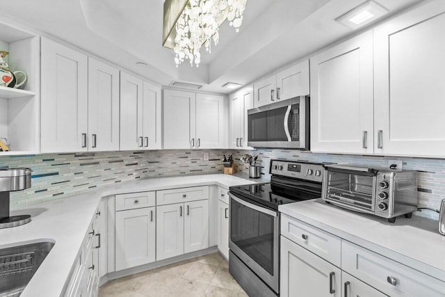 kitchen with tasteful backsplash, stainless steel appliances, a raised ceiling, and white cabinets