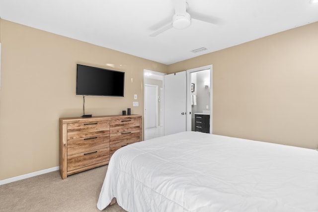 bedroom featuring light colored carpet, ceiling fan, and ensuite bathroom