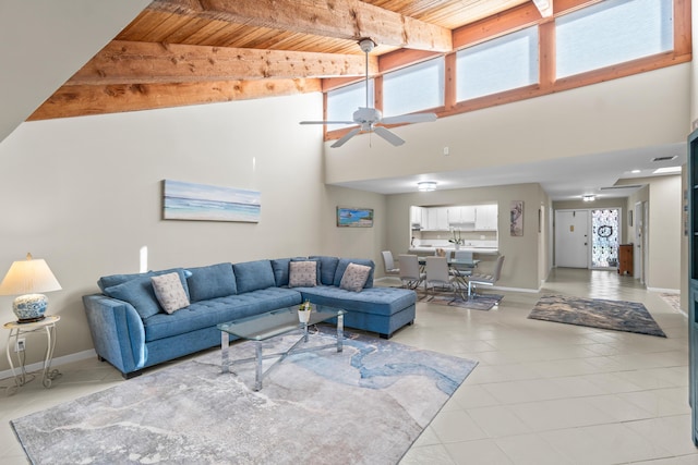 living room featuring light tile patterned flooring, wood ceiling, a towering ceiling, ceiling fan, and beam ceiling