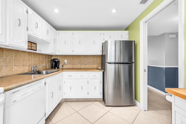 kitchen with white cabinets, light tile patterned floors, stainless steel refrigerator, and dishwasher