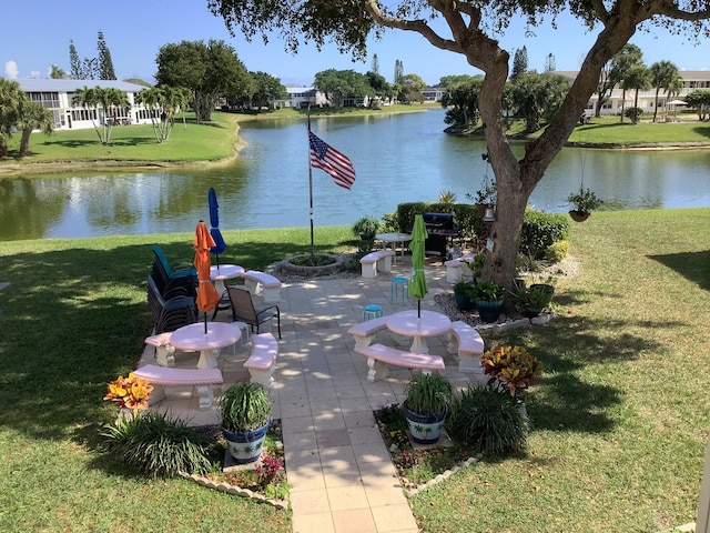 view of community featuring a patio, a lawn, and a water view