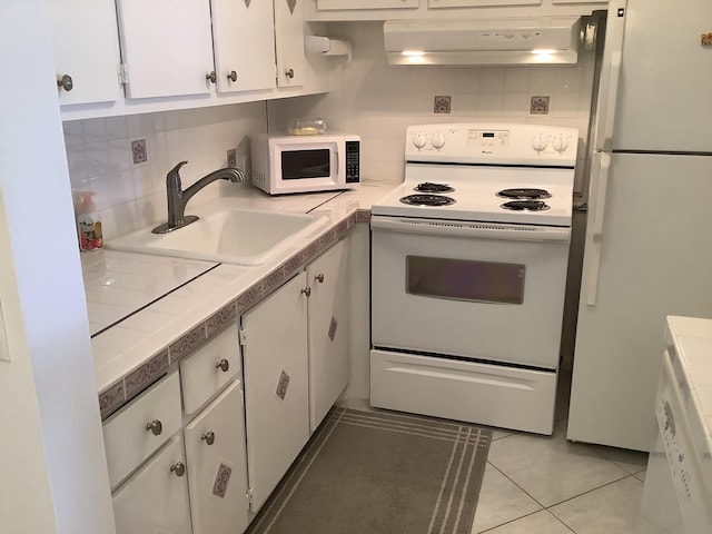 kitchen featuring range hood, tasteful backsplash, sink, white cabinets, and white appliances