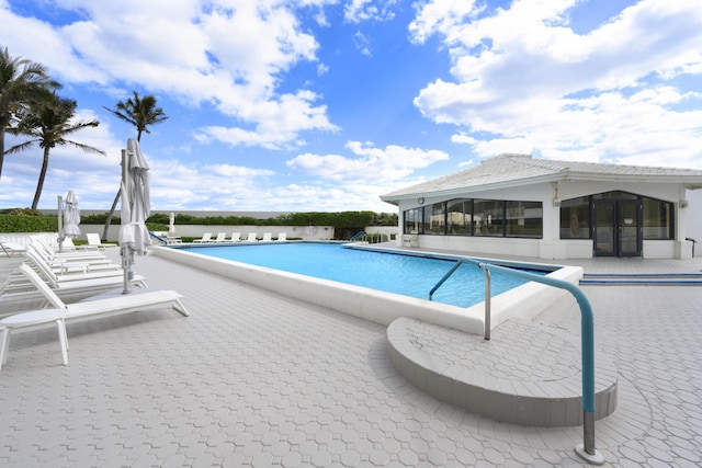 view of swimming pool featuring a sunroom and a patio area