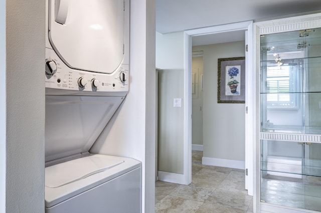 laundry area with light tile patterned floors and stacked washer / dryer