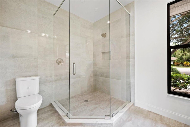 bathroom featuring a wealth of natural light, a shower with shower door, and toilet