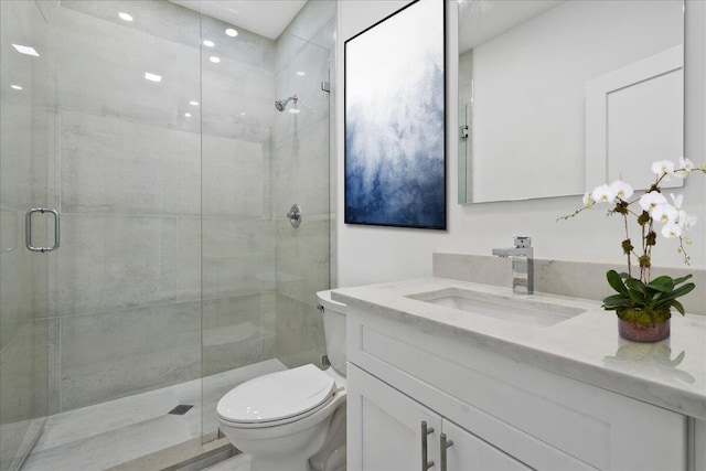 bathroom featuring a shower with door, vanity, and toilet