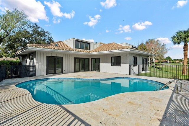 back of property with a fenced in pool and a patio