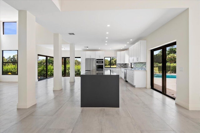 kitchen with white cabinetry, a kitchen island, backsplash, and appliances with stainless steel finishes