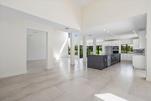 kitchen featuring sink, backsplash, stainless steel appliances, a center island, and white cabinets