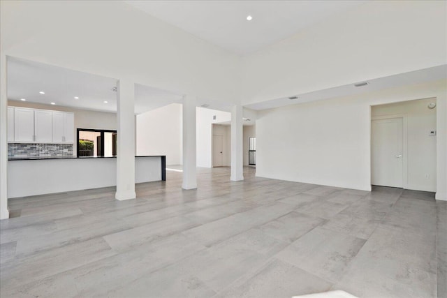 unfurnished living room featuring a towering ceiling