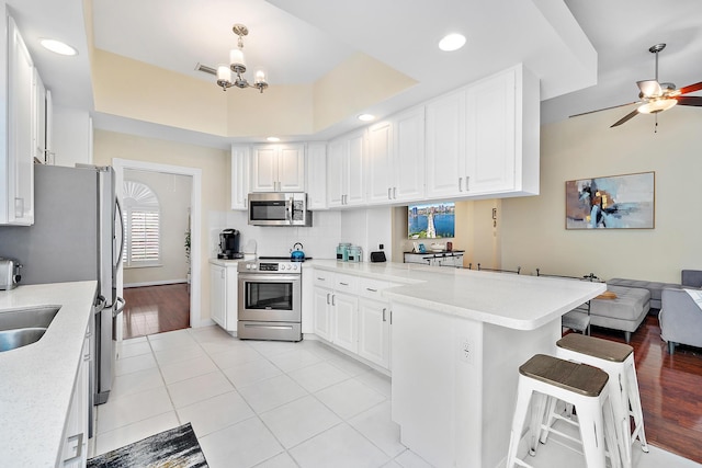 kitchen with appliances with stainless steel finishes, kitchen peninsula, and white cabinets