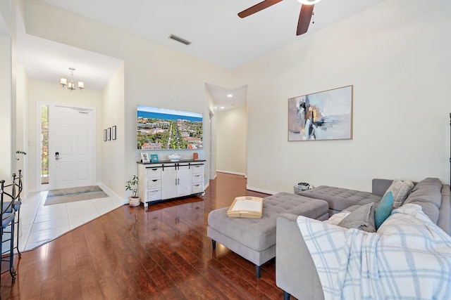 living room featuring ceiling fan with notable chandelier and dark wood-type flooring