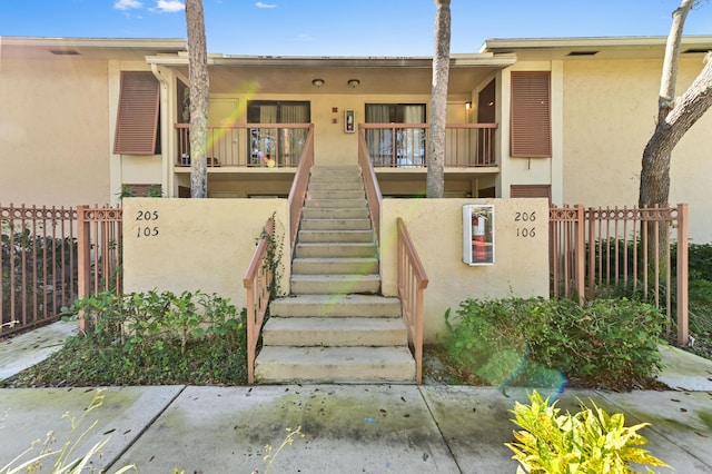 exterior space with stairway, fence, and stucco siding