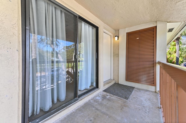 entrance to property featuring a balcony and stucco siding