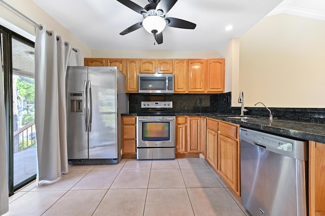 kitchen featuring light tile patterned floors, tasteful backsplash, appliances with stainless steel finishes, a sink, and dark stone counters