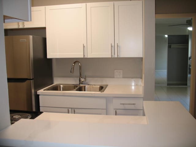 kitchen featuring ceiling fan, a sink, white cabinetry, freestanding refrigerator, and tile patterned floors