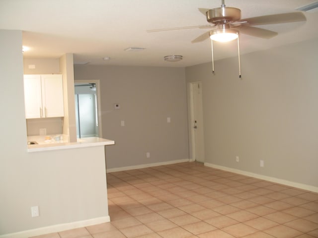 spare room featuring light tile patterned floors, baseboards, visible vents, and a ceiling fan