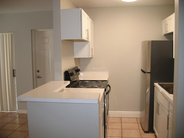 kitchen with light tile patterned floors, range with electric cooktop, white cabinets, freestanding refrigerator, and light countertops