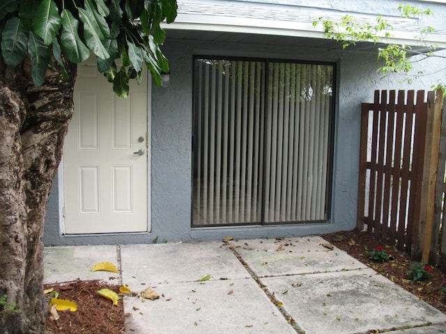 entrance to property with fence and stucco siding