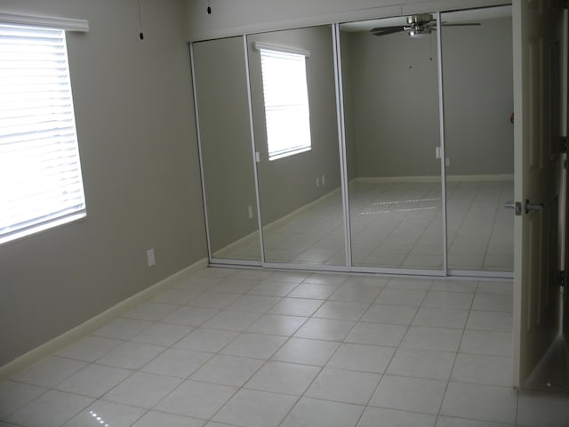 unfurnished bedroom with a ceiling fan, baseboards, a closet, and light tile patterned flooring