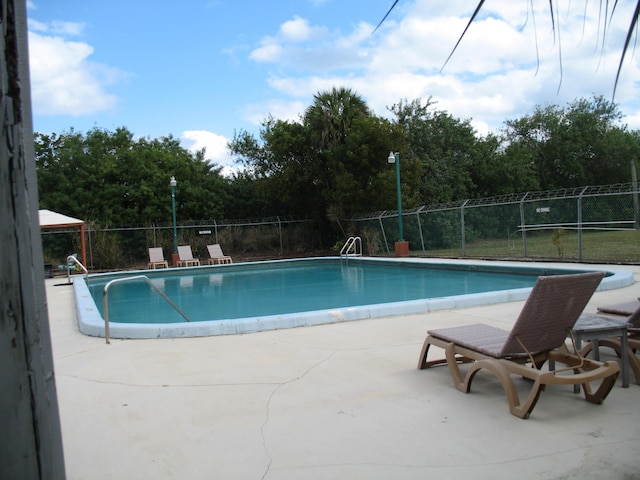 pool featuring fence and a patio