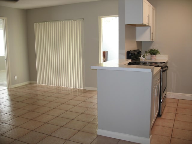 kitchen featuring light tile patterned floors, white cabinetry, light countertops, and range with electric stovetop