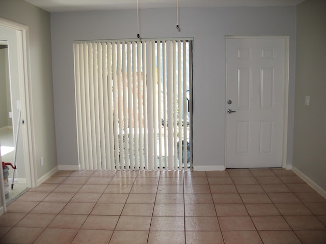 unfurnished room with light tile patterned floors and baseboards