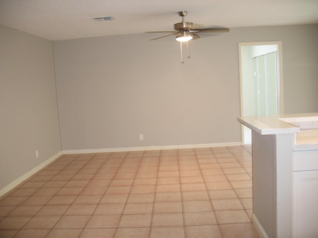 unfurnished room featuring a ceiling fan, visible vents, baseboards, and light tile patterned floors