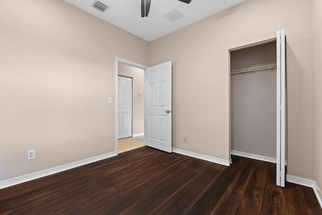 unfurnished bedroom featuring ceiling fan, dark hardwood / wood-style flooring, and a closet